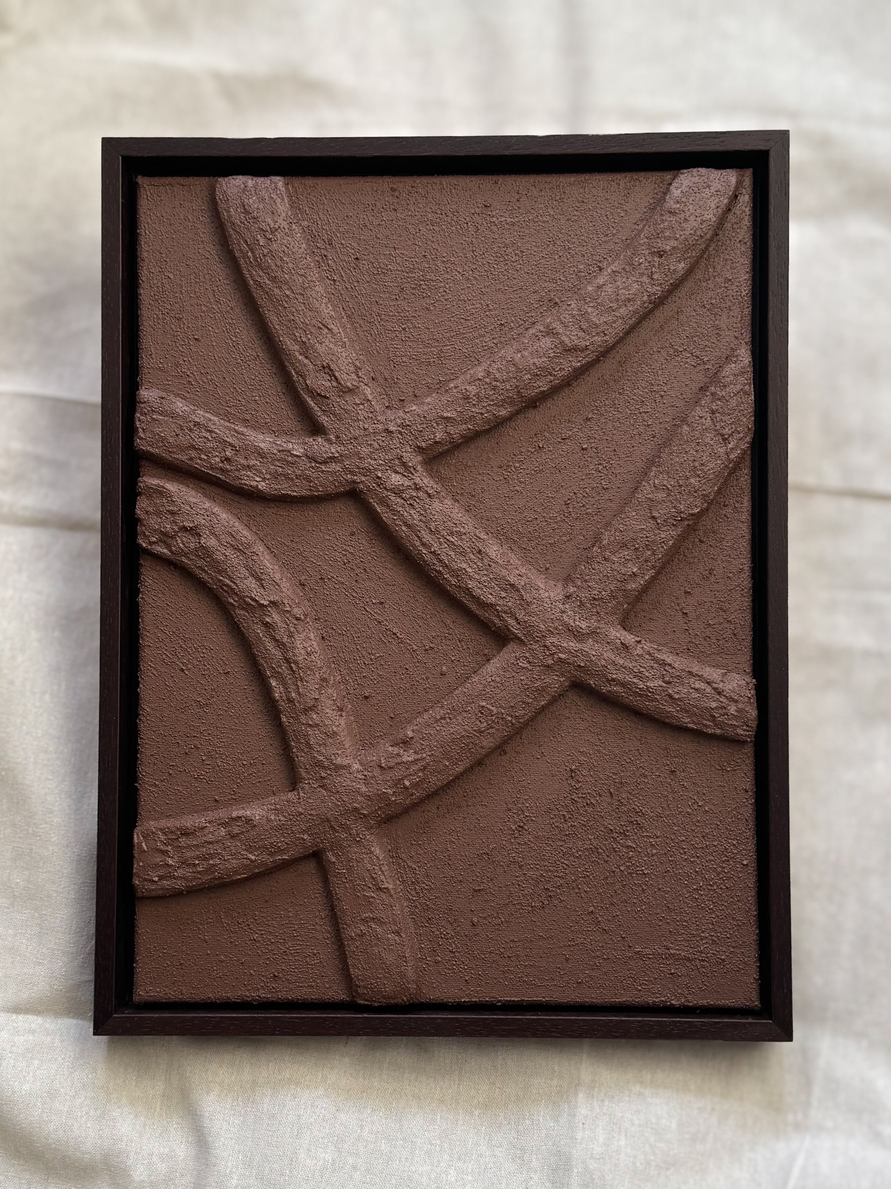 Abstract reliëf kunstwerk in chocoladebruin met houten lijst, organische lijnen en natuurlijke textuur, passend in een Japandi of wabi-sabi interieur, handgemaakt door Studio Lamain.