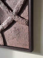 Detail van abstract reliëf wandkunst in chocoladebruin aan de muur in een rustig interieur, met houten lijst en organische vormen, handgemaakt door Studio Lamain.