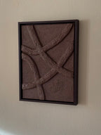 Abstract reliëf wandkunst in chocoladebruin aan de muur in een rustig interieur, met houten lijst en organische vormen, handgemaakt door Studio Lamain.