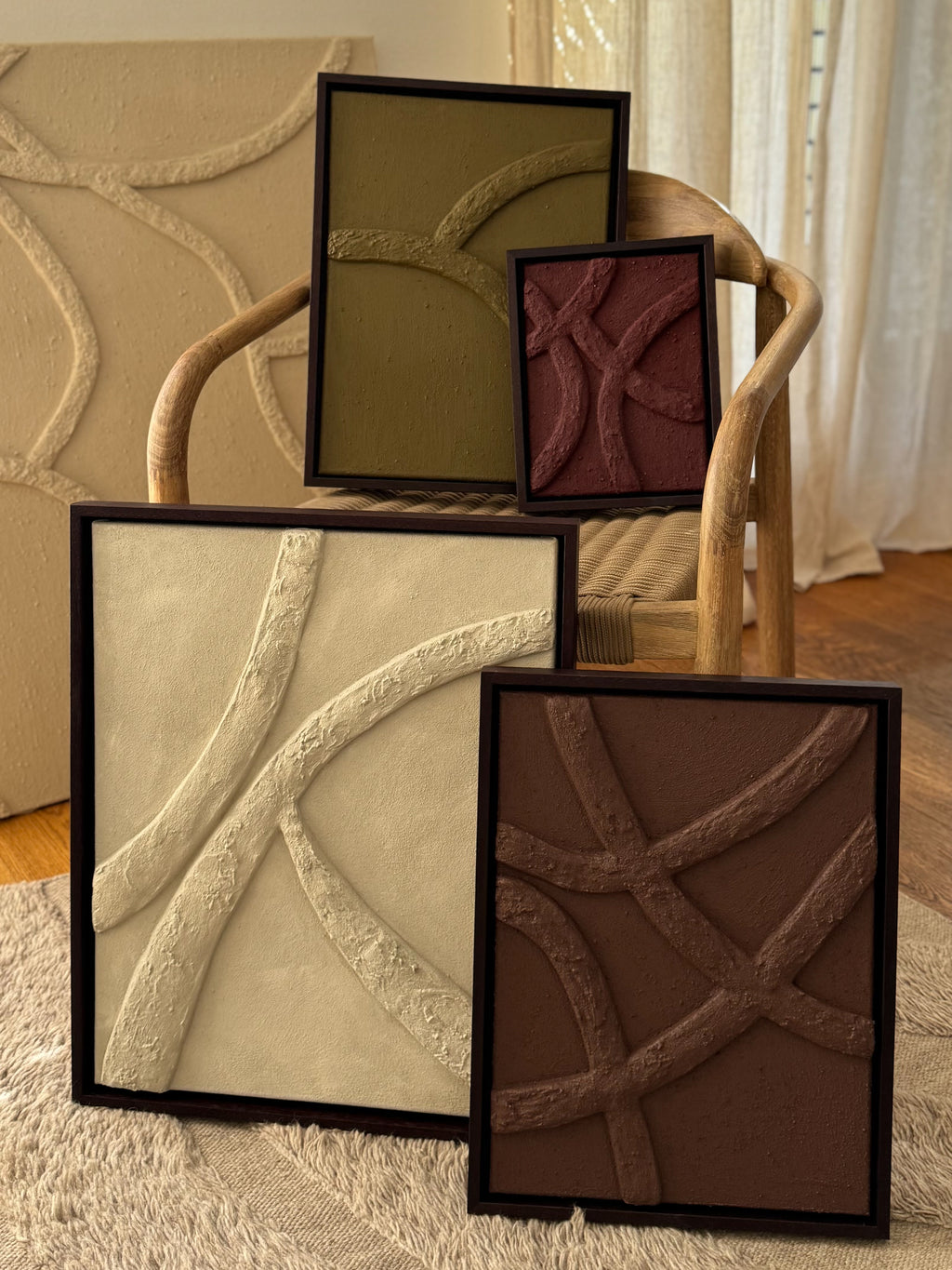 Overzicht van meerdere abstracte reliëf kunstwerken in natuurlijke kleuren met houten lijsten en organische lijnen, handgemaakt door Studio Lamain.