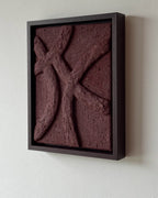 Een handgemaakt abstract reliëf kunstwerk in bordeauxrood met houten lijst en organische lijnen en structuur aan de muur.