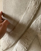 Hand met detail van de textuur van een handgemaakt reliëf kunstwerk met organische lijnen en structuur.