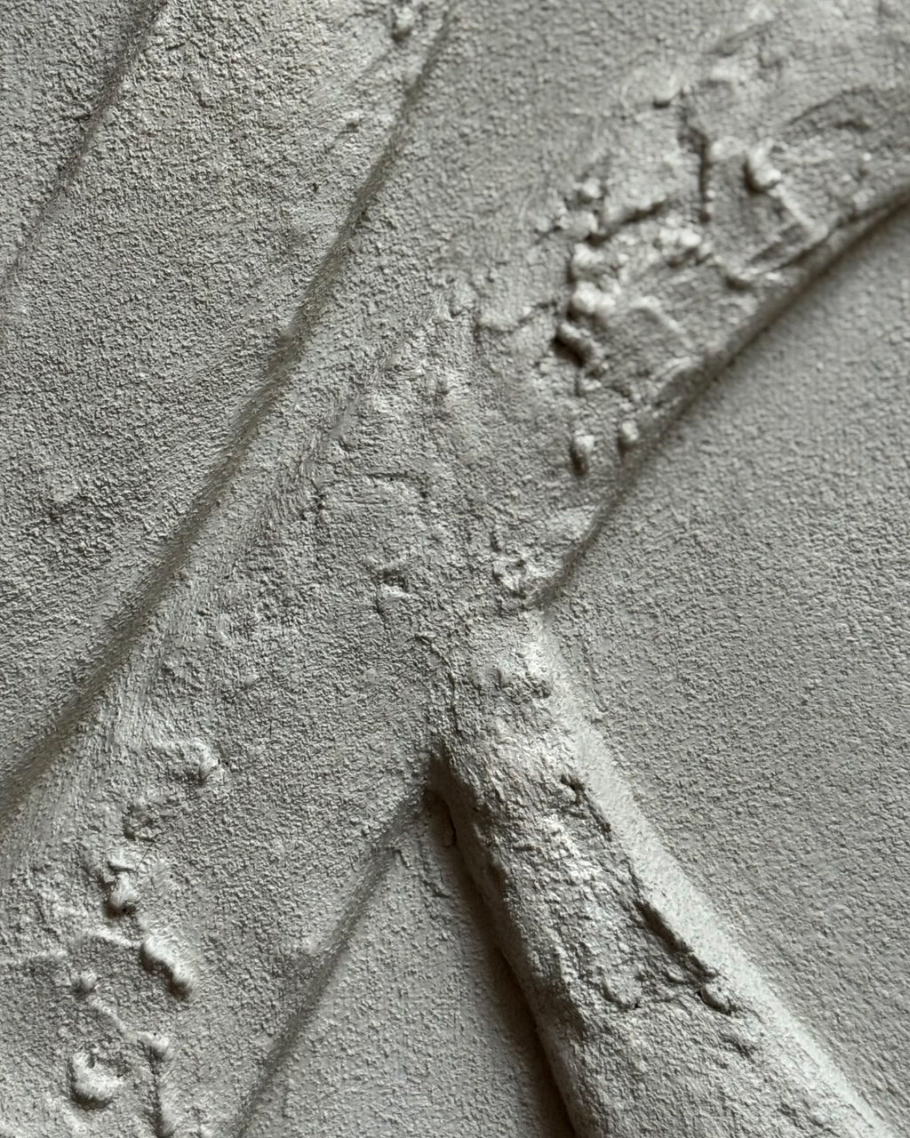 Detail van handgemaakte zandkleurig reliëf kunstwerk met organische lijnen en gelaagde structuur. 