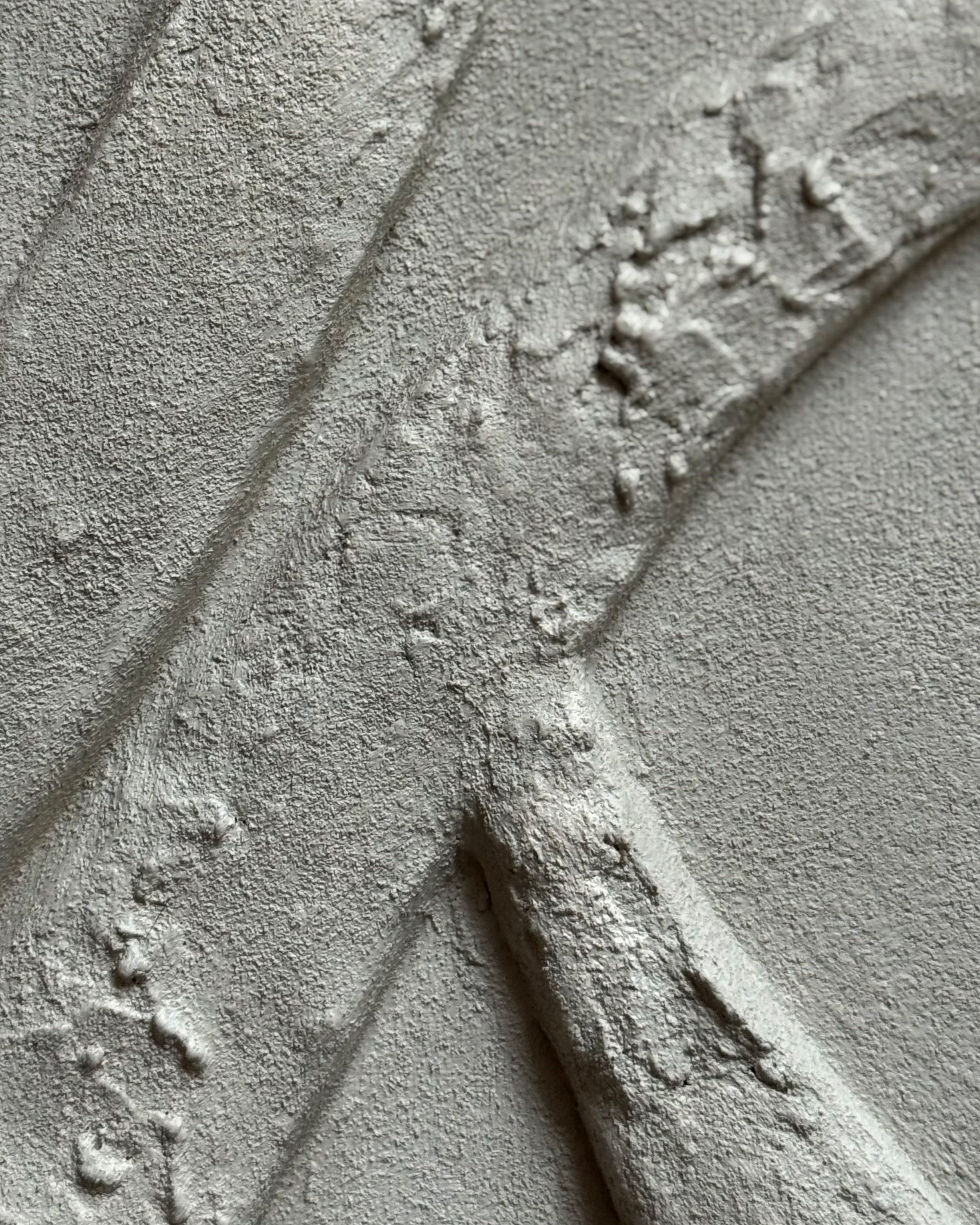 Detail van handgemaakte zandkleurig reliëf kunstwerk met organische lijnen en gelaagde structuur. 