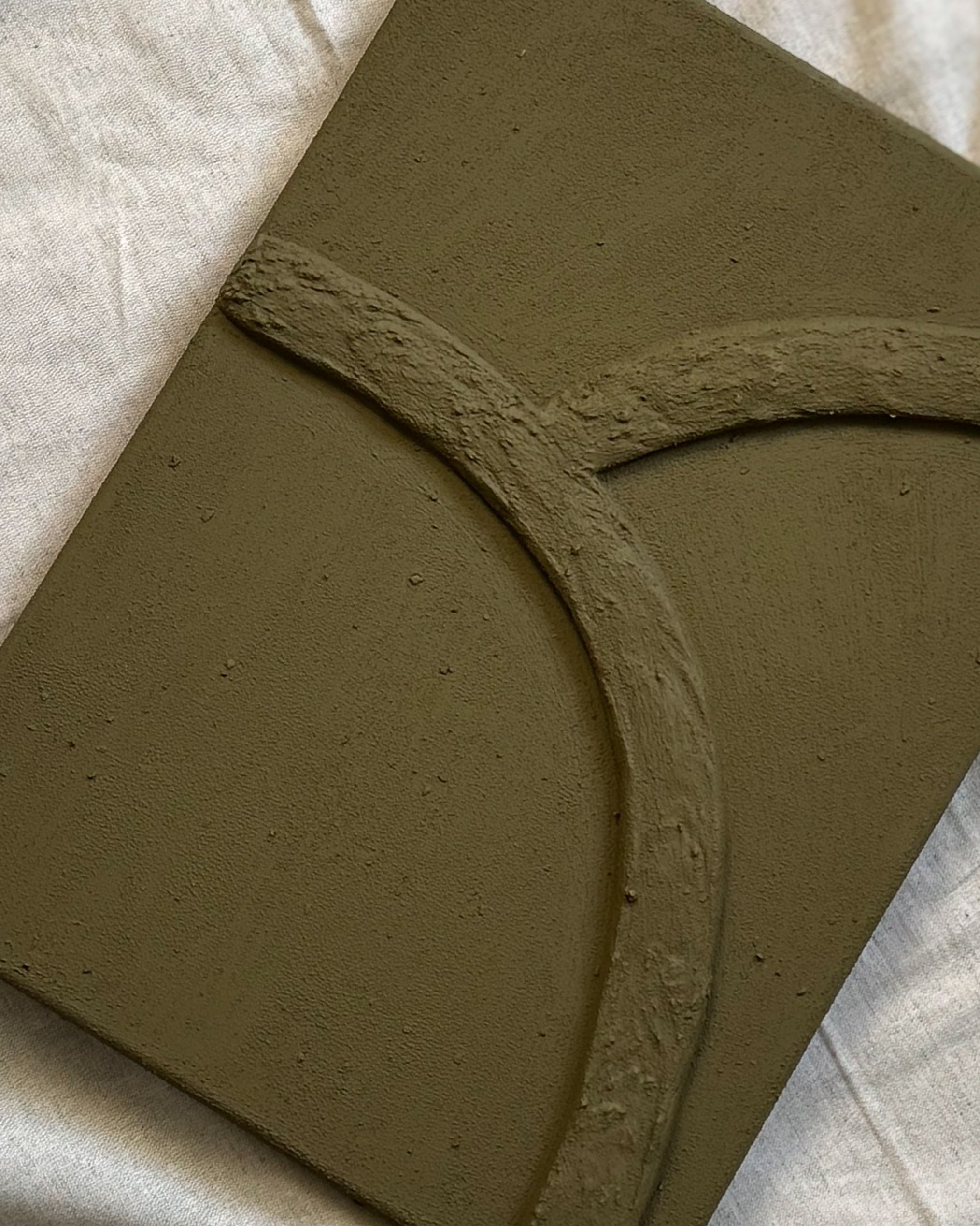 Closeup van abstract reliëf kunstwerk in olijfgroene kleur met organische lijnen en natuurlijke textuur, handgemaakt door Studio Lamain.