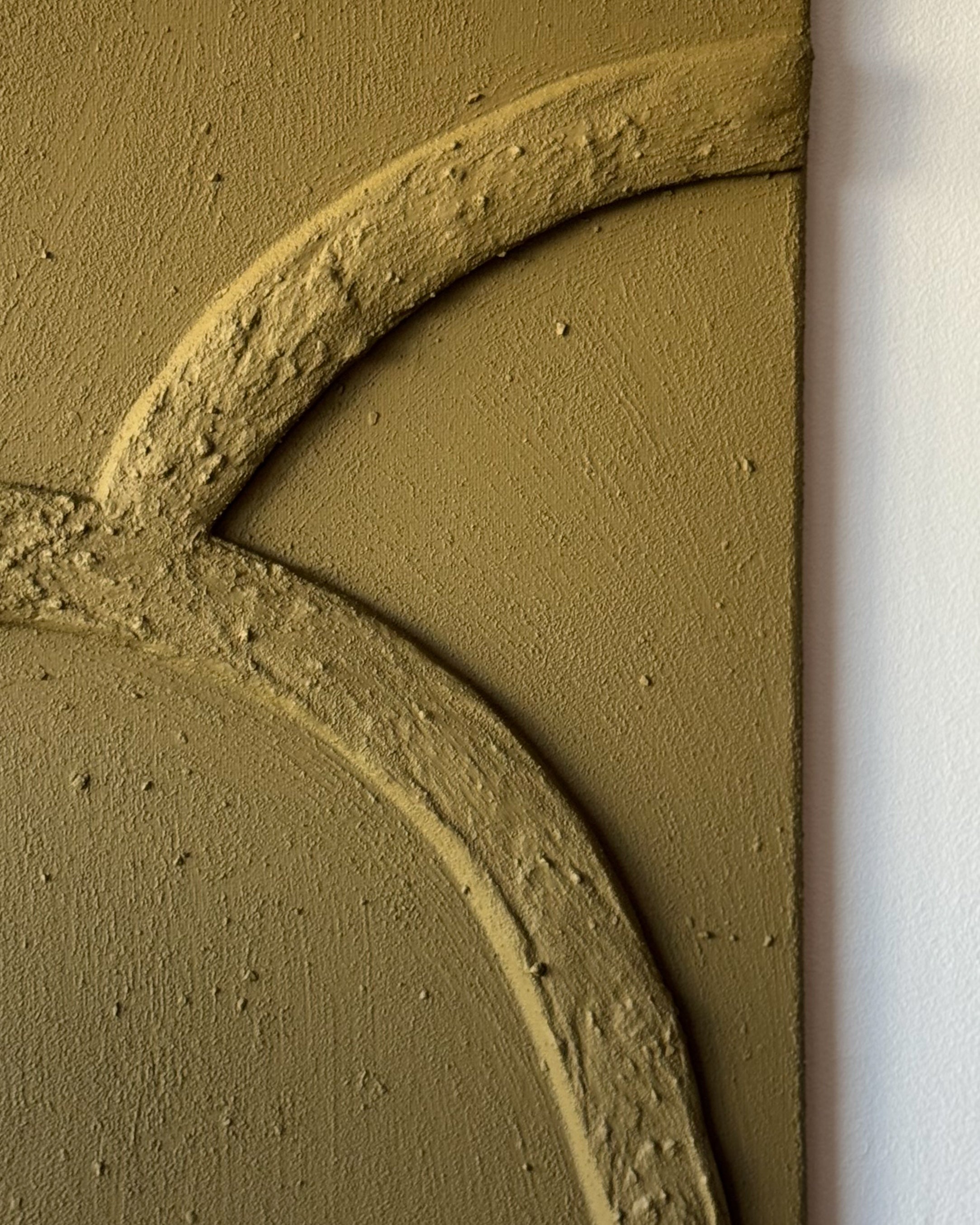 Detail van abstract reliëf kunstwerk in olijfgroene kleur met organische lijnen en natuurlijke textuur aan de muur, handgemaakt door Studio Lamain.