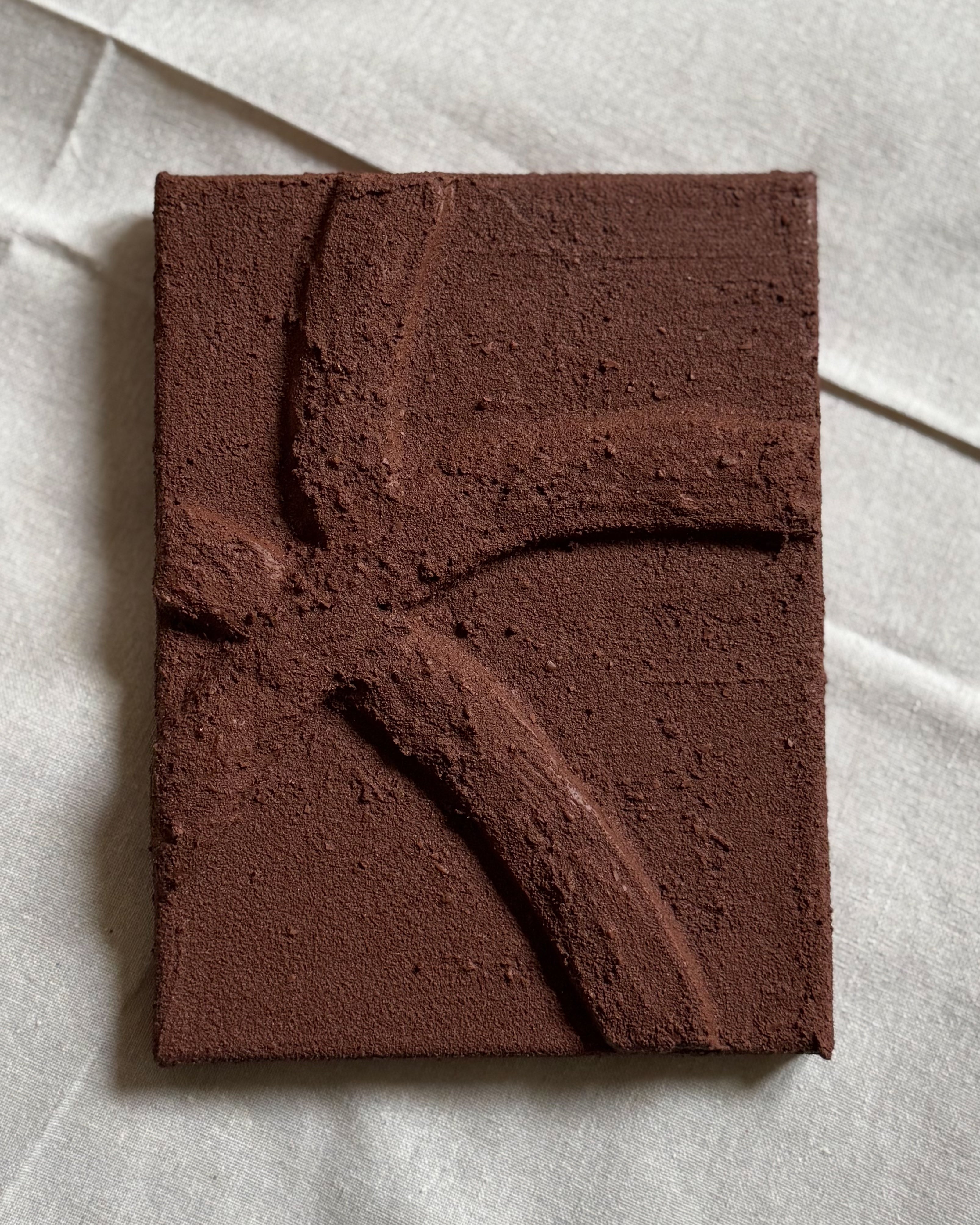 Een abstract chocoladebruin reliëf kunstwerk met organische lijnen en voelbare structuur. 