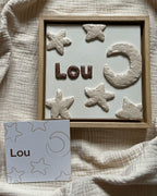 Handgemaakt reliëfkunstwerk met naam Lou, gebaseerd op zijn geboortekaartje met sterren en de maan in zachte aardetinten.