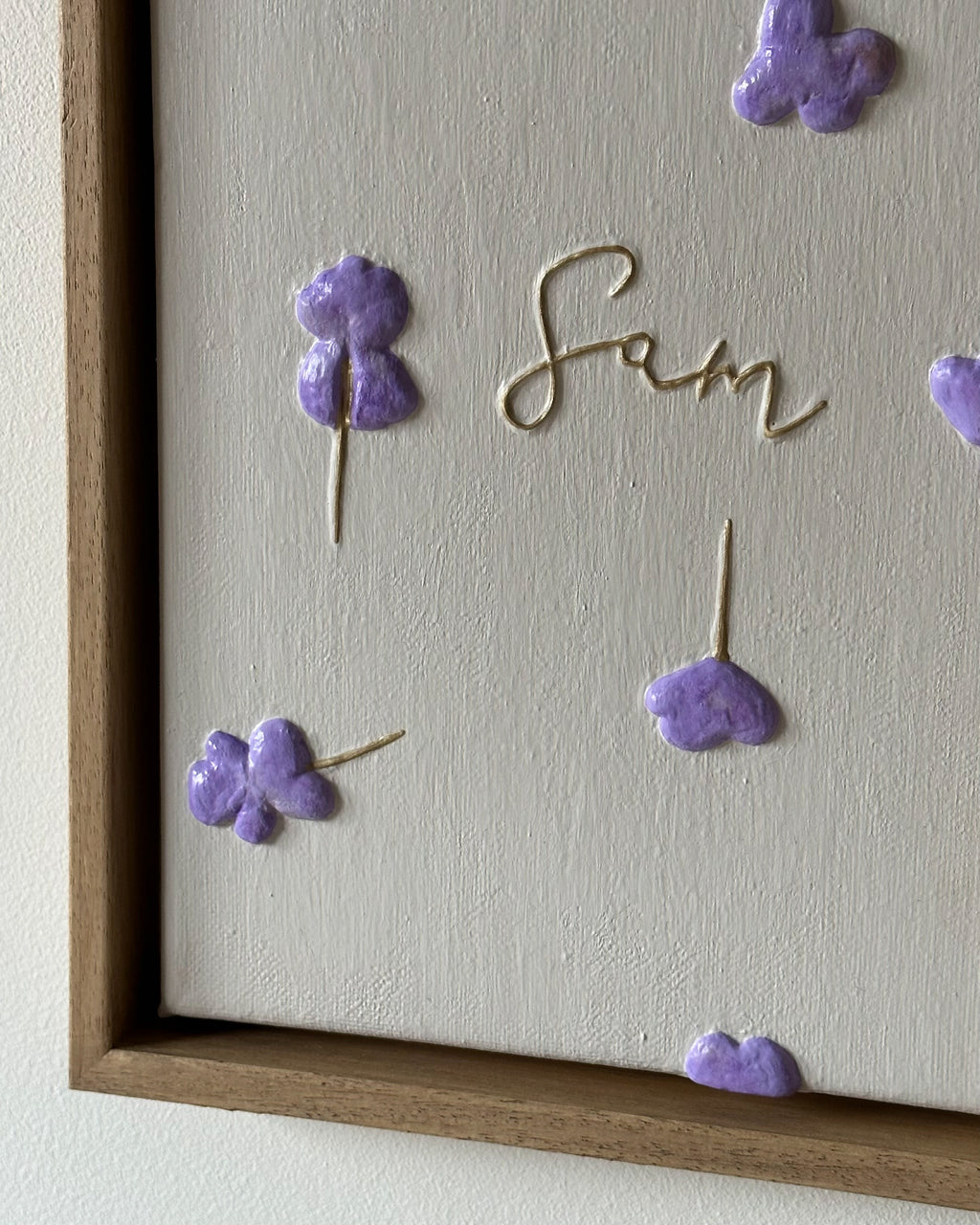 Detail van reliëfkunstwerk gebaseerd op geboortekaartje op canvas voor Sam met lila bloemen en zachte tinten aan muur.