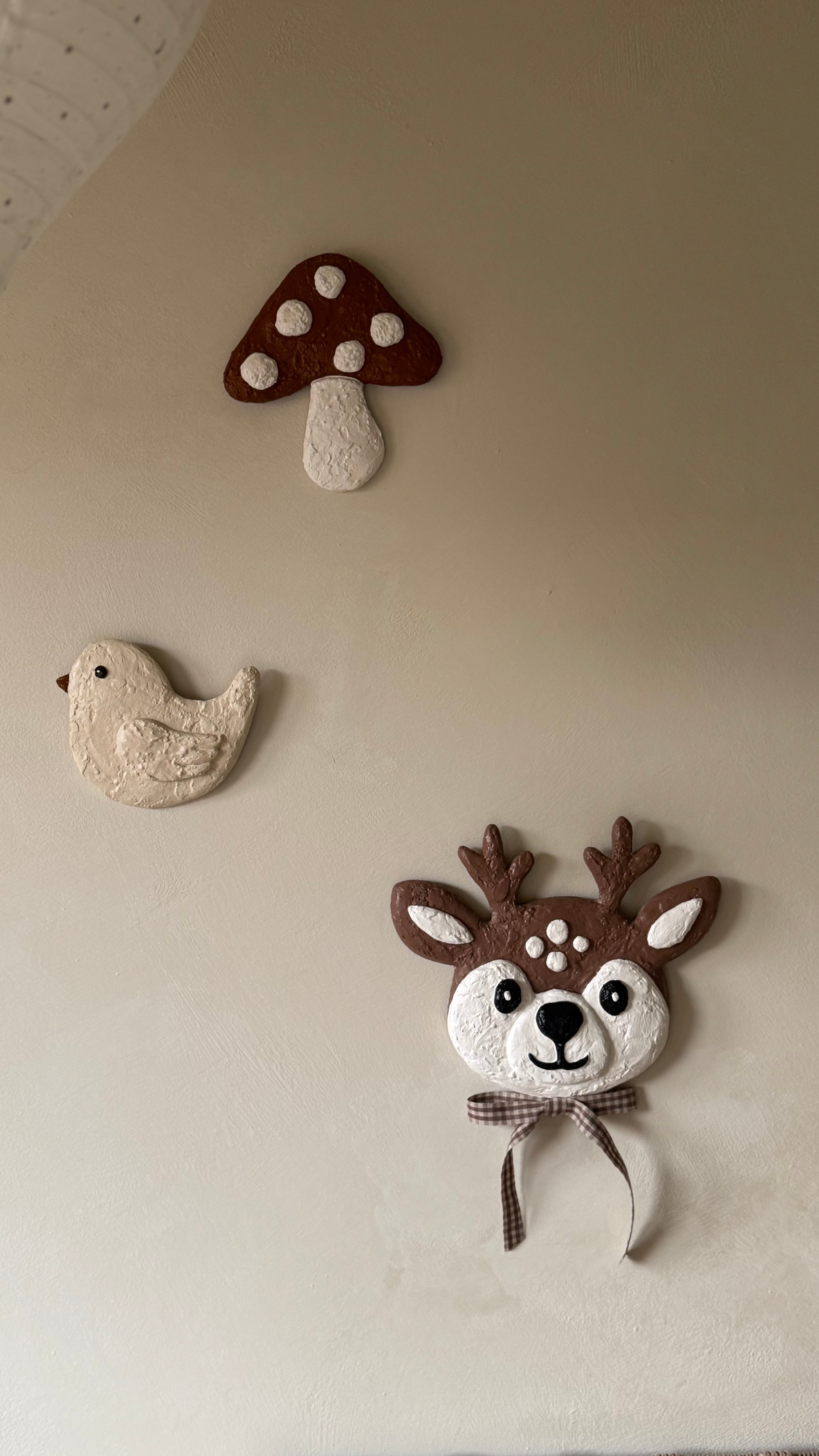 Handgemaakte wandobjecten voor de kinderkamer van Studio Lamain: een vogel, paddenstoel en hertje in 3D en zachte tinten. 