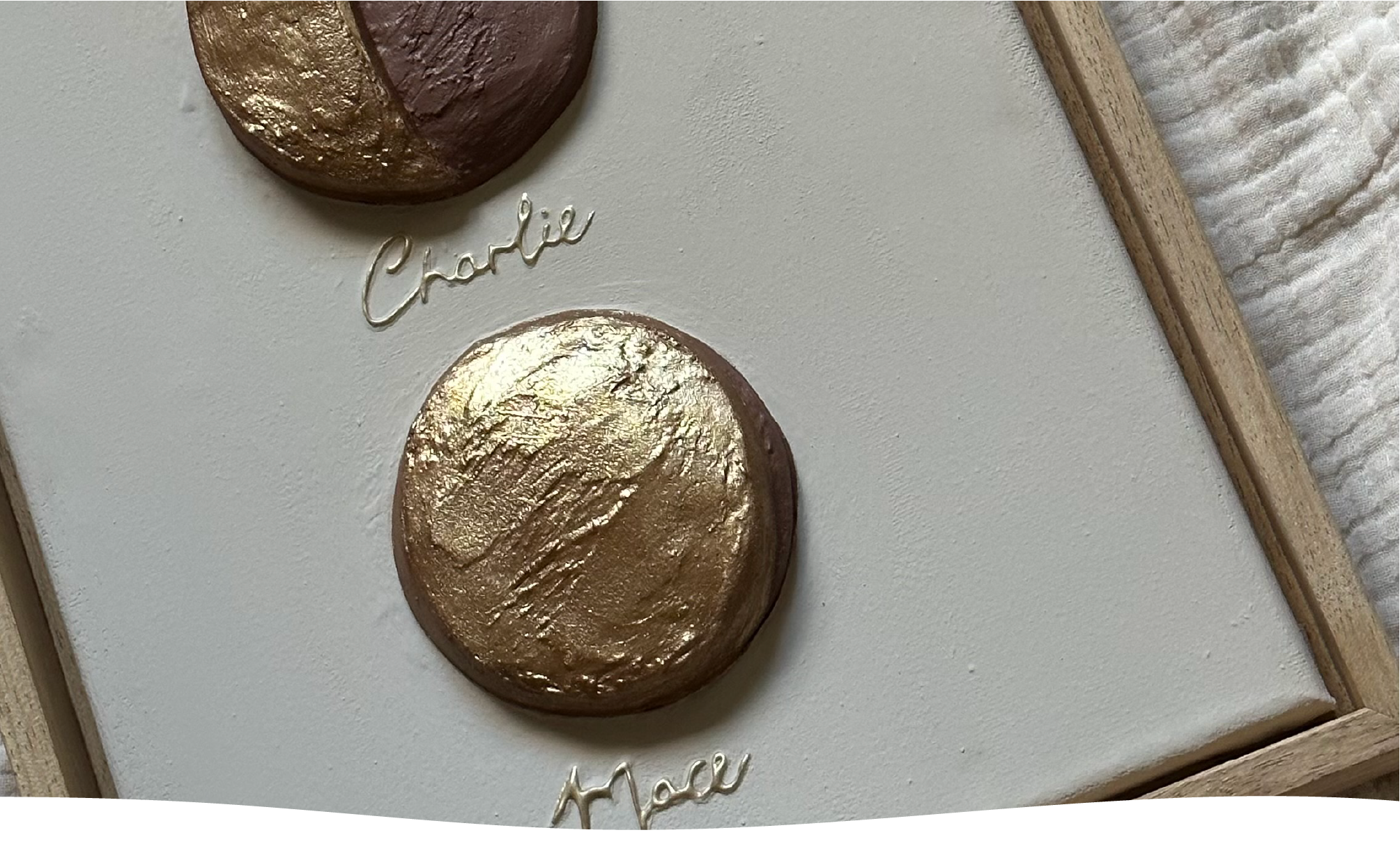 Een detailbeeld van de maanfase van Charlie en Mace, een reliëfkunstwerk op canvas in zachte tinten en goud-brons.