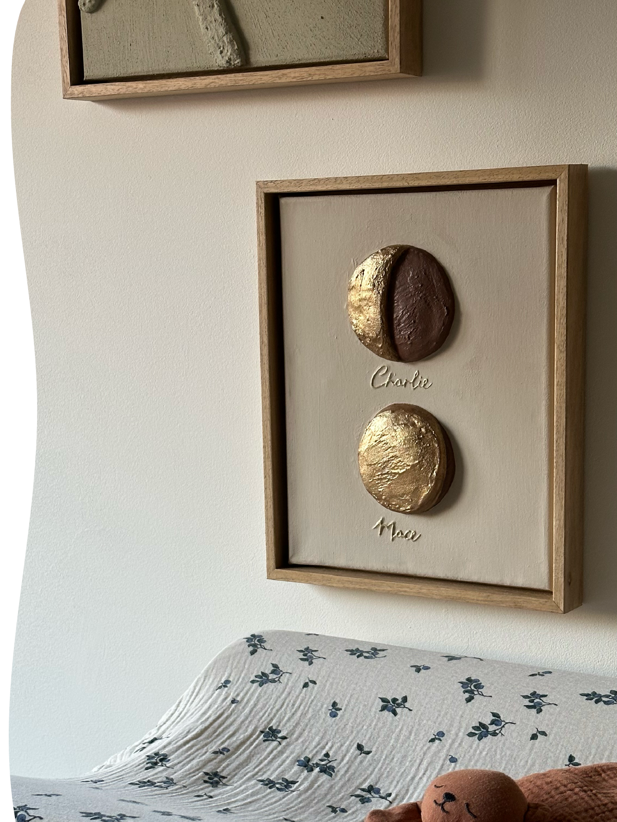 Een reliëfkunstwerk met maanfase van de geboortedagen van Charlie en Mace samen, in zachte tinten met goud-brons en een houten lijst.