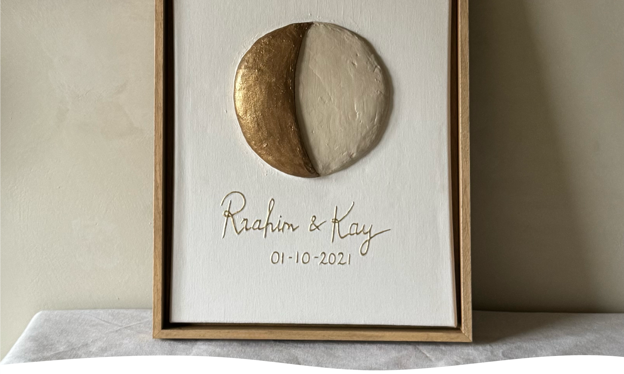 Maanfase op canvas van trouwdatum van Rrahim en Kay in reliëf in neutrale tinten.