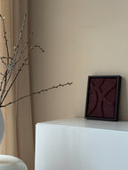 Het bordeauxrode handgemaakte 3D kunstwerk in noten houten lijst van Studio Lamain in een rustig beige interieur.
